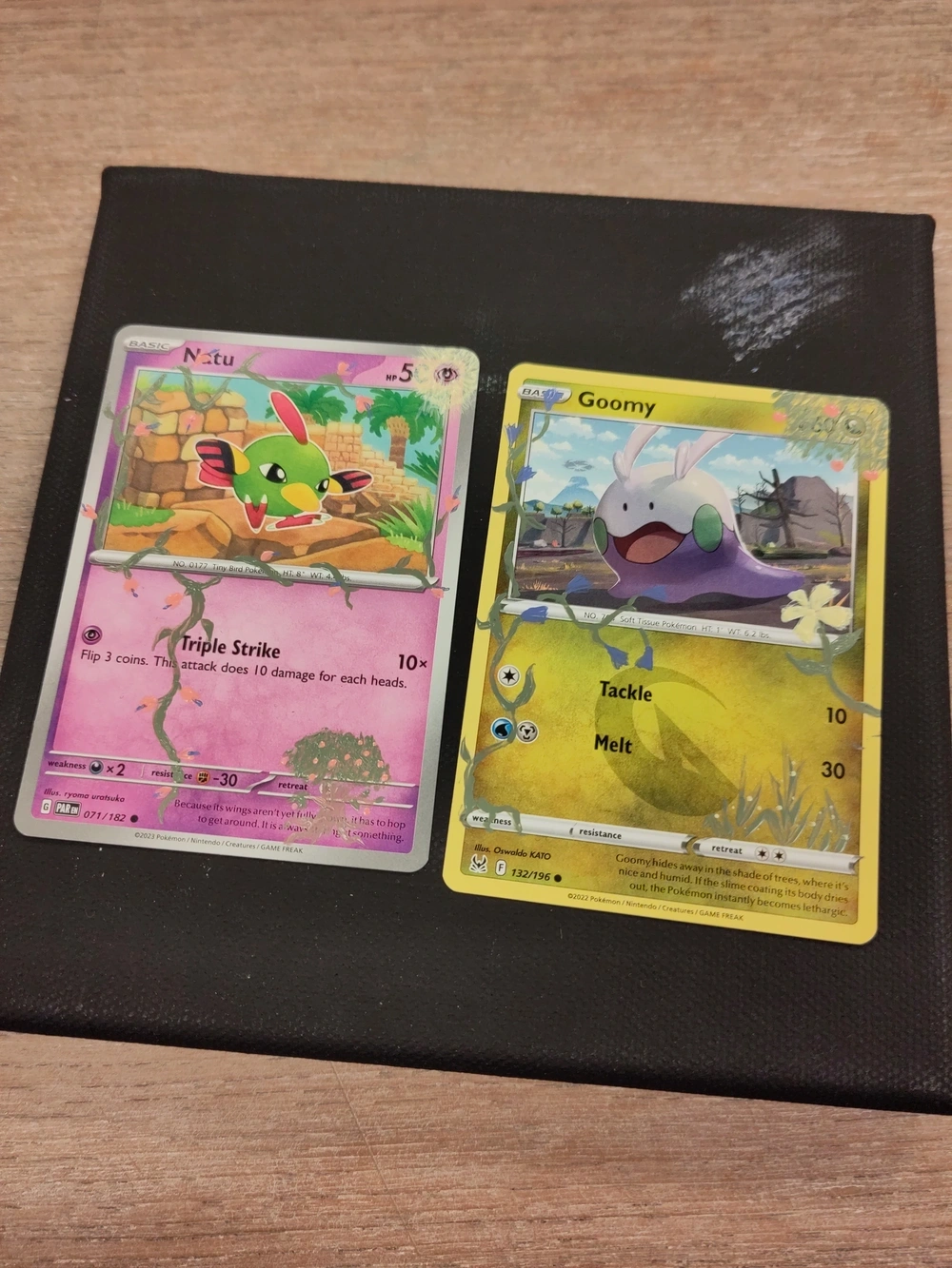 Natu and Goomy Pokémon cards with vines and flowers hand painted on them.