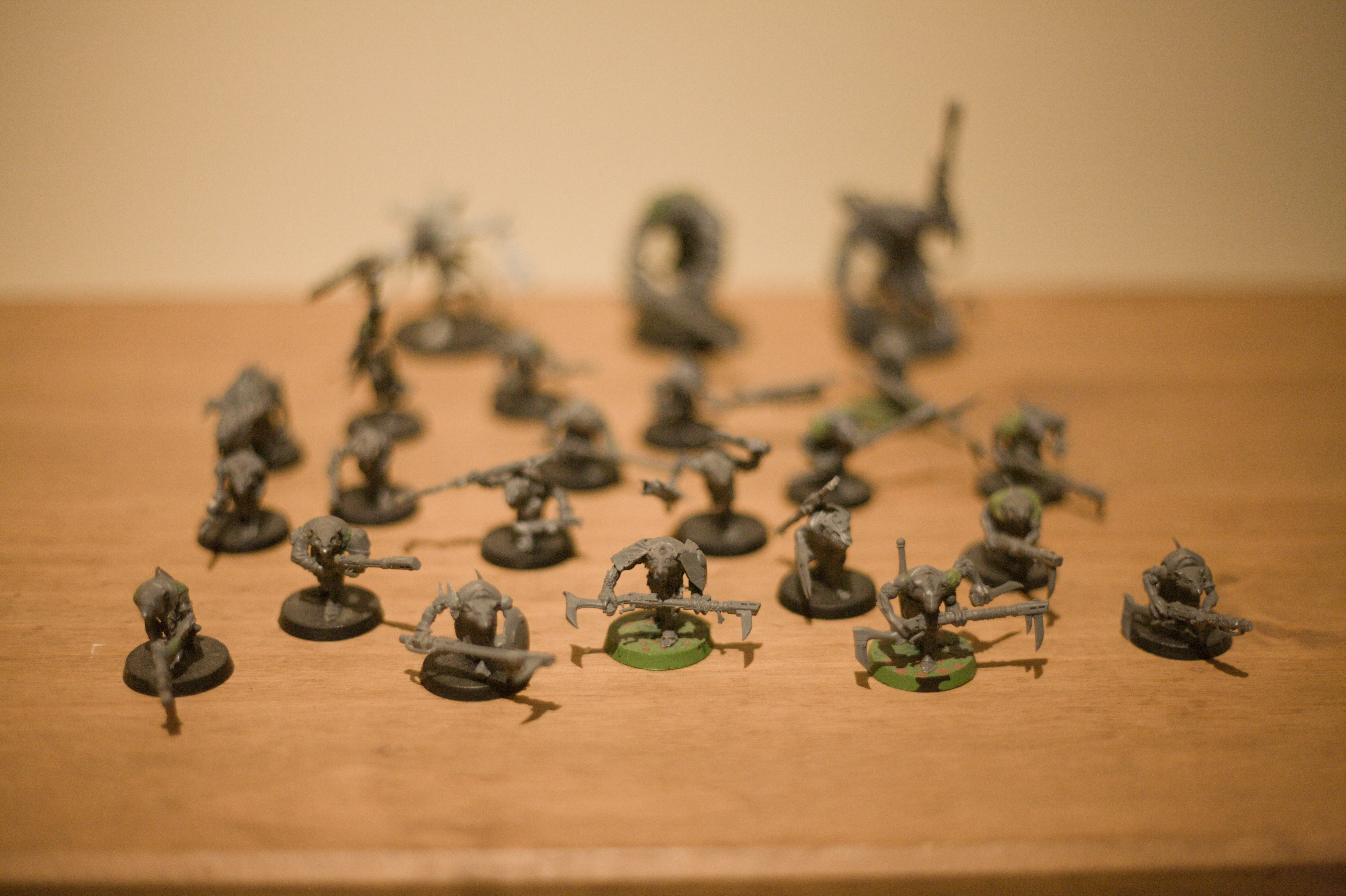 Another set of miniatures: Rat men armed with various mismatched rifles and daggers, some with mechanical or extra limbs. Larger rat men with bigger guns stand in the back. The front row is in focus. None of them are painted.